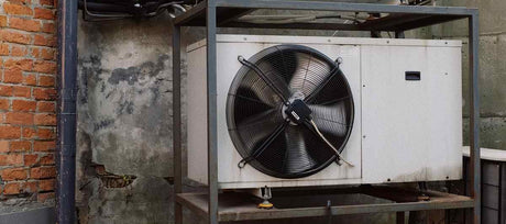 Industrial, old AC unit outside on shelf against brick wall